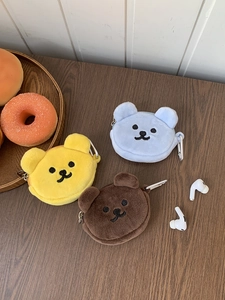 Close-up of plush bear coin purses with zippers and carabiners on a wooden table