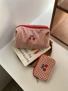 Detail of red gingham cherry makeup bags showing embroidery and fabric texture