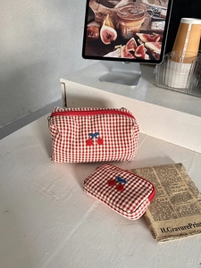 Detailed set of cherry embroidery red checkered cosmetic bags on a vintage desk