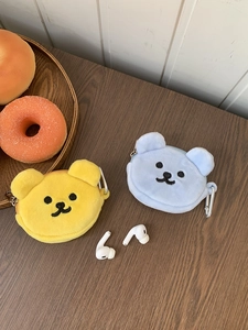 Detail of plush bear earphone cases with metal carabiner clips on a wood background