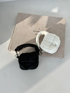 Dettaglio mini custodia trapuntata per auricolari, trama gonfia in bianco e nero