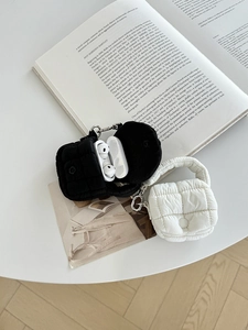 Dettaglio di mini custodie per auricolari trapuntate in nero e bianco su un libro