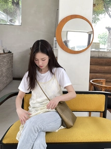 Detail of a bronze woven crossbody bag paired with a stylish summer vacation outfit