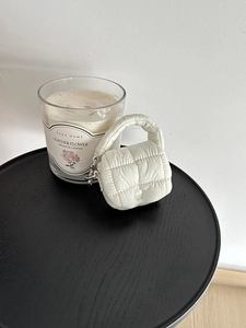 Dettaglio mini borsa trapuntata bianca con anello metallico su tavolo di legno nero