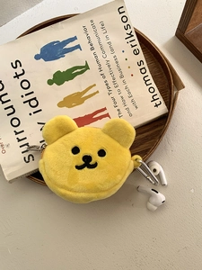 Close-up of a yellow plush bear earphone pouch with metal carabiner on a book