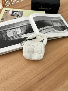 Dettaglio mini borsa trapuntata bianca con gancio argento su una scrivania di legno