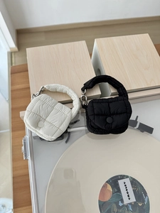 Dettaglio di mini borse trapuntate in nylon beige e nero su un giradischi vintage