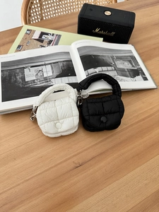 Dettaglio di mini pochette trapuntate in bianco e nero con clip su tavolo in legno