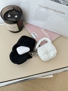 Dettaglio di mini custodie trapuntate per auricolari in nero e bianco con ganci
