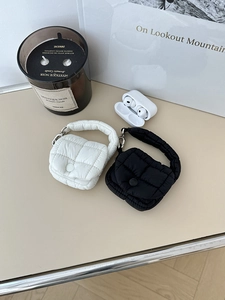 Dettaglio delle mini borse trapuntate per auricolari in bianco e nero con fibbia