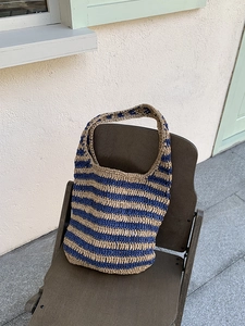 Detail of blue and beige striped woven tote bag placed on a classic wooden chair