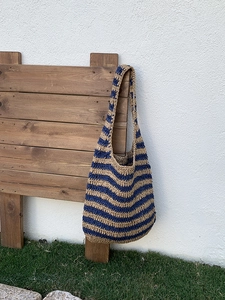 Close-up of the woven texture on a striped straw hobo bag with blue and beige patterns