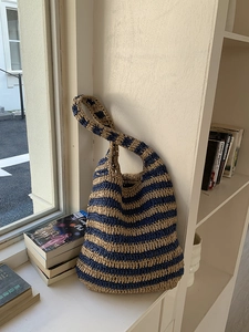 Detail view of the hand-woven straw bucket bag with blue and beige stripes texture