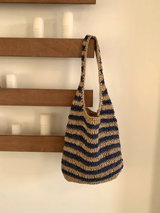 Blue and beige woven straw shoulder bag in a striped pattern for summer vacations