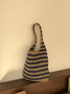 Detailed close-up of a handwoven straw bucket bag with navy and khaki stripes