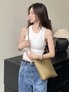 Minimalist gold woven shoulder bag with fine metal chain strap shown in lifestyle scene