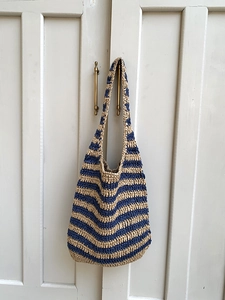 Detail of hand-woven striped tote bag hanging on a vintage door handle