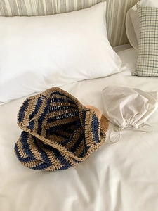 Summer woven straw bucket bag with blue and brown stripes on white bedding