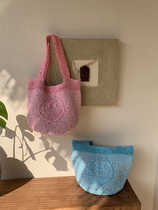 Close-up detail of handmade crochet smiley face tote bags in pink and blue knit