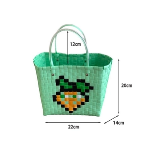 Detail of mint green woven tote bag with carrot pattern and clear plastic handles