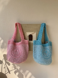 Detail of pink and blue crochet mini tote bags with smiley patterns on a textured wall