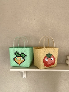 Close-up of woven beach bags featuring pixel art carrot and tomato designs and clear handles