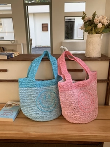 Detail of handmade bohemian knit mini tote bags with smiley face texture in blue and pink