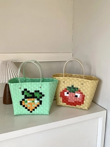 Macro detail of woven picnic bags with pixelated vegetable patterns and plastic handles