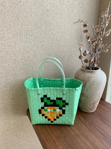 Detail of woven beach tote showing carrot pattern and transparent tube handles