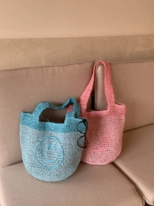 Detailed knit texture of a handmade crochet mini tote bag featuring a yellow smiley face