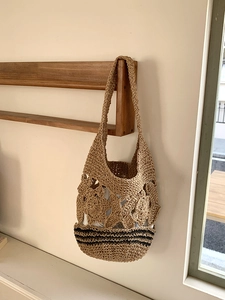 Détail de la maille fleurie ajourée et du fond rayé noir sur le sac cabas en paille