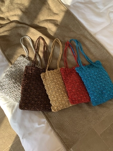 Top view of five hand-woven crochet shoulder bags in assorted metallic yarn colors