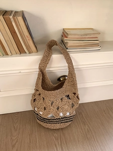 Détail du sac cabas en paille tissé avec motif floral ajouré et base à rayures brunes