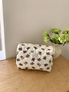 Gros plan d'une trousse à maquillage blanche matelassée avec des motifs d'ours colorés