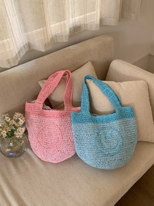Detail showing two handmade crochet mini tote bags with cute smile patterns and striped lining