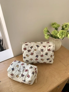 Ensemble de trousses à maquillage matelassées à motifs d'ours sur une table en bois