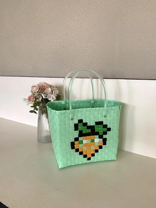 Detail of hand-woven green tote bag with pixel carrot pattern and clear round handles