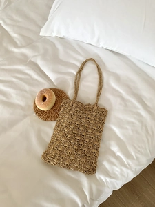 Detail of hand-woven hollow wave pattern on khaki straw shoulder bag for vacation