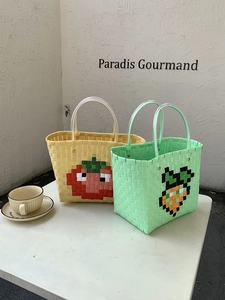 Detail of hand-woven plastic beach bags with pixelated strawberry and carrot patterns
