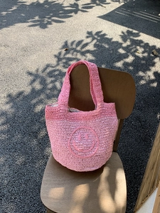 Close-up of pink handmade crochet smiley mini bag on a vintage wooden chair