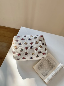 Détail macro de la trousse de maquillage en coton matelassé à motifs d'ours sur un bureau