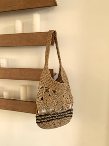 Détail du sac cabas en paille tissé à la main avec motif floral ajouré et rayures noires