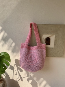 Close-up of pink handmade crochet tote bag with smiley face and striped lining detail
