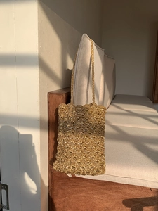 Detailed close-up of golden handmade crochet shoulder bag with metallic thread texture