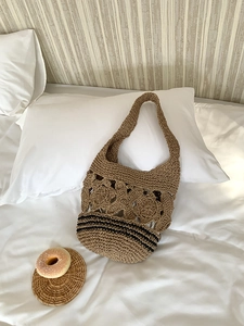Détails de motifs floraux crochetés et rayures noires sur un sac fourre-tout en paille