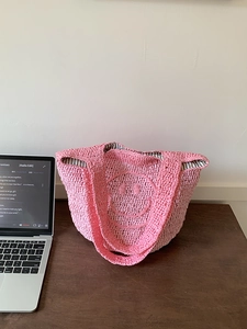 Detail of pink hand-crocheted smiley face tote bag with striped fabric lining