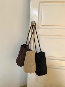 Détails de sacs seaux tissés à la main en noir, kaki et marron foncé sur un support