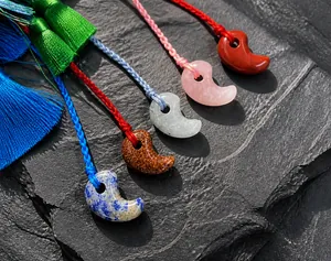 Close-up of magatama natural stone pendant with colorful handmade tassel and cord