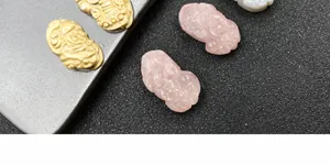 Makroaufnahme von handgeschnitzten Anhängern aus rosa Kristall mit Pixiu-Motiv