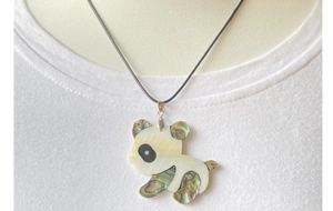Détail macro d'un pendentif panda en nacre et coquille d'abalone sur un cordon noir